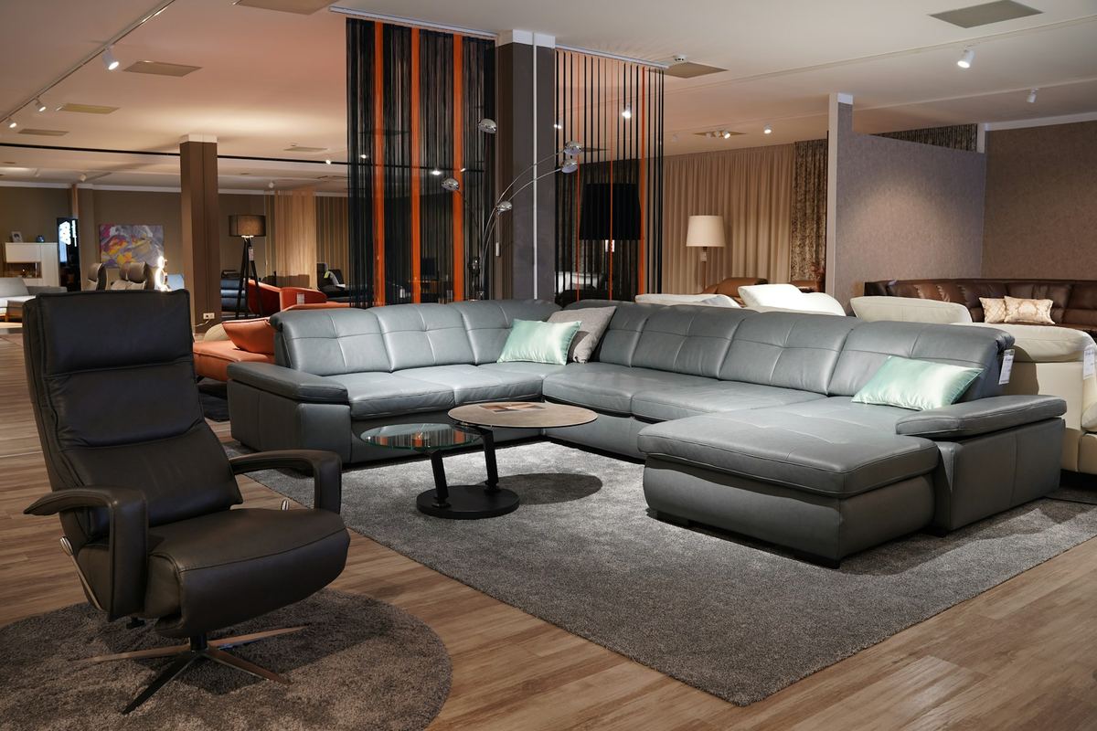 Showroom met een grijze hoekbank en een leren fauteuil